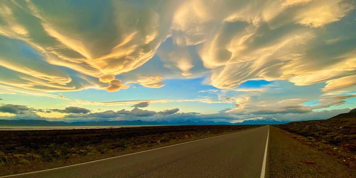 Straight stretch of Provincial Route 41 across the steppe, under lenticular clouds lit by the sunset