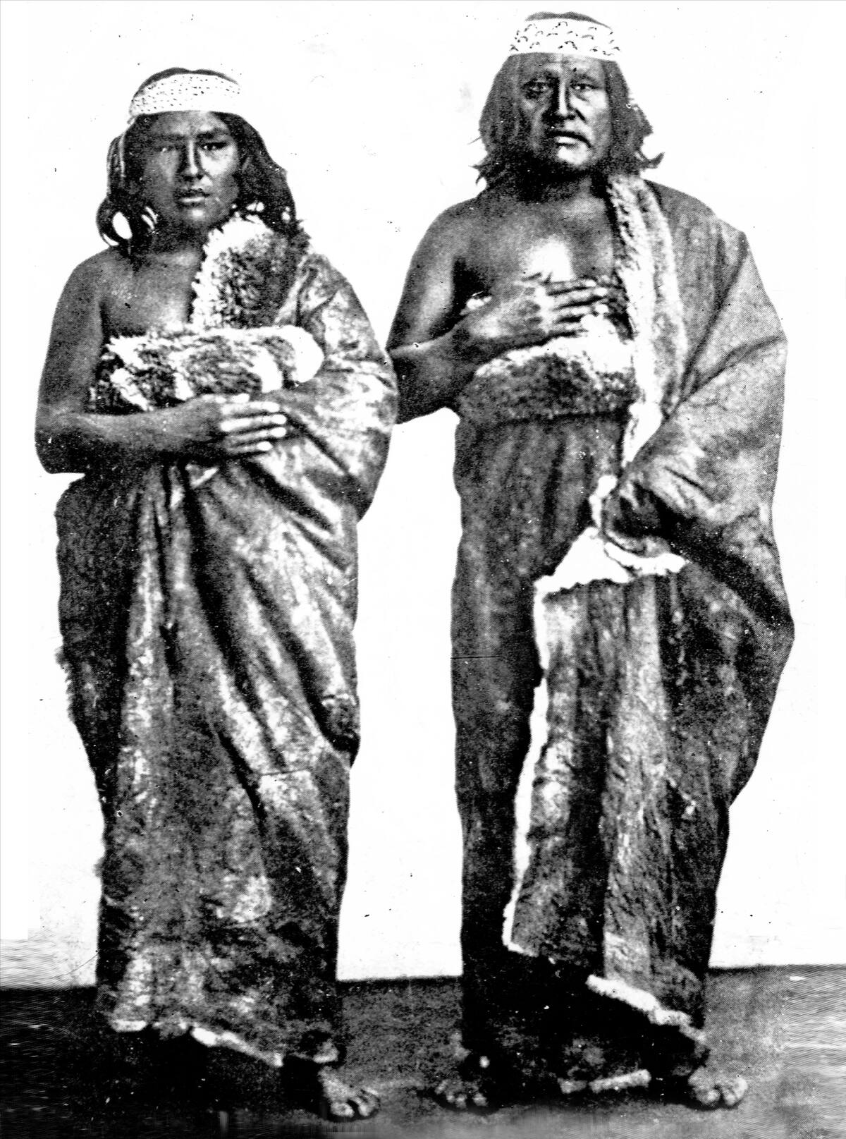 Black-and-white studio portrait of Tehuelche chief Casimiro Biguá and his son, standing, wrapped in guanaco-skin cloaks