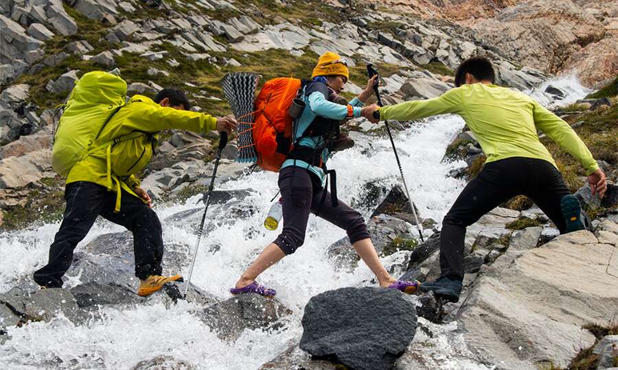 Grupo de fotógrafos cruzando un arroyo de montaña